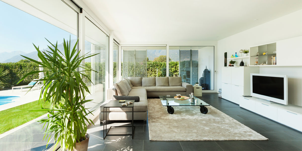 Modernes Wohnzimmer mit Glasfronten und Panorama-Aussicht sowie Swimmingpool im Garten.
